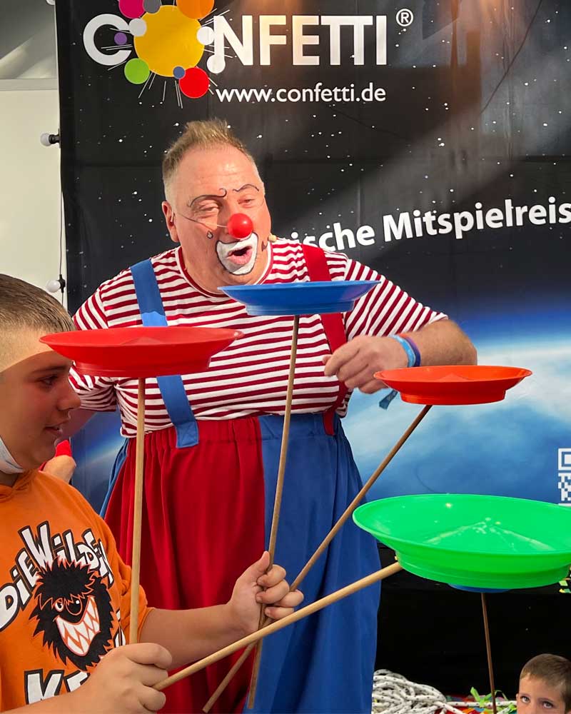 Clown Püppi begeistert Kinder auf der SPIEL Essen 2025 mit seiner bunten Jonglier- und Mitmachshow von Confetti.de